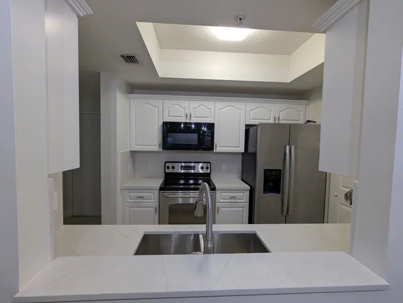 After: view of the white kitchen and new countertops through the pass-through, Coral Gables