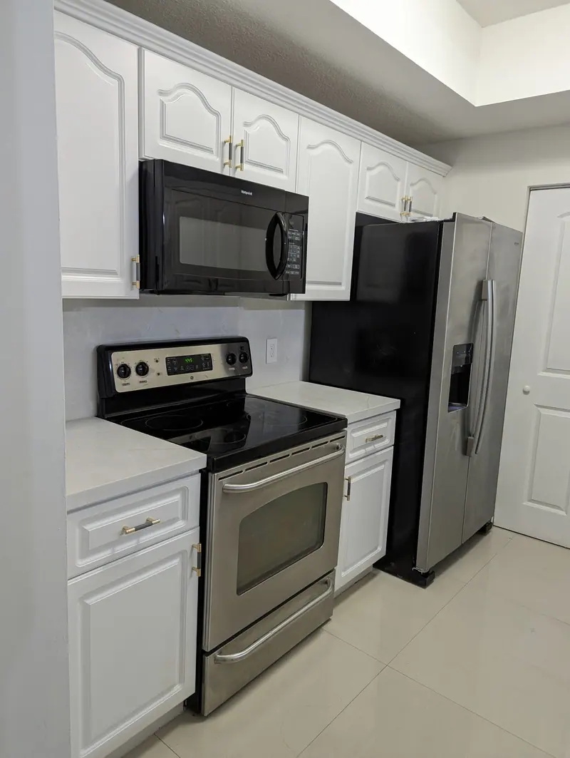 After: white cabinets with stainless range, microwave and refrigerator, Coral Gables