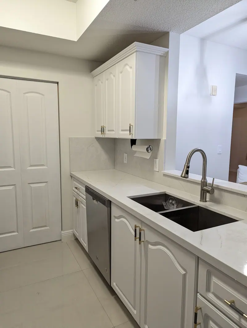 After: white Snowbound cabinets and new white countertop along the sink wall, Coral Gables