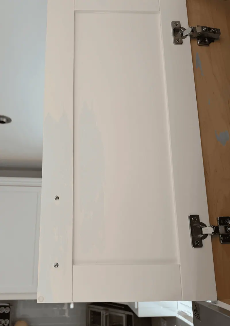 Another cabinet door with yellowish tannin bleed through the old white finish