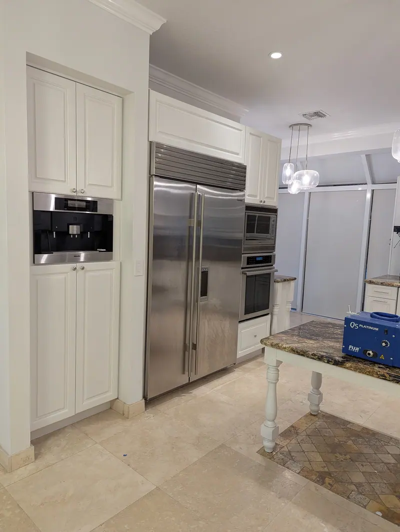 Aventura kitchen after painting, white cabinets beside the stainless steel refrigerator