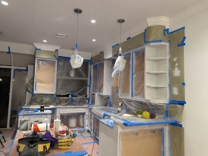 Aventura kitchen masked with plastic sheeting and tape for on-site cabinet spraying