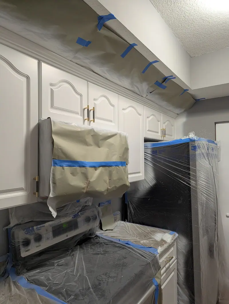 Coral Gables kitchen masked with plastic and paper during on-site cabinet spraying