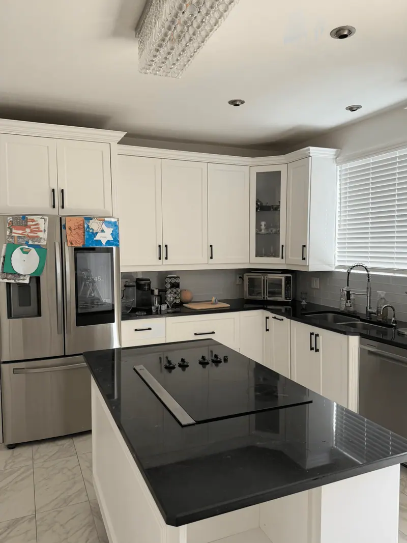 Hallandale Beach kitchen with refinished white cabinets and black countertops after tannin bleed correction