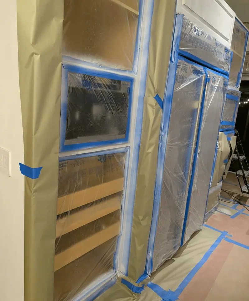 Oak cabinet doors taped and masked during prep in the Aventura kitchen