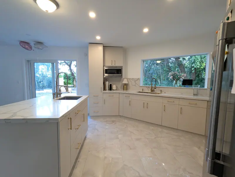 Wide view of the refinished Fort Lauderdale kitchen with beige cabinets and white island